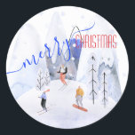 Pegatina Redonda Merry Christmas Snowy Mountain Sceners Skiers<br><div class="desc">Un pintoresco,  lindo y feliz pegatina de Feliz Navidad pintado con acuarelas de esquiadores esquiando en una montaña con nieve y árboles y una bella caligrafía moderna diciendo Feliz Navidad.</div>