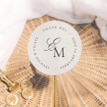 Pegatina Redonda Minimalist Monogram Wedding Thank You Favor<br><div class="desc">A thank you sticker to match our Editorial Photo Wedding collection. The monogram features script calligraphy and a classic serif font in a unique layout. A message of your choice is printed in serif typography around the monogram, creating a circular frame. The background is an off-white ivory color. This favor...</div>