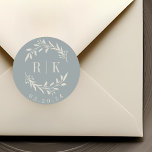 Pegatina Redonda Monograma del Boda de guirnaldas botánicas rustica<br><div class="desc">pegatinas en monograma de boda botánico diseñado por personalizados que presentan una elegante corona beige blanca con las iniciales de la pareja y la fecha boda sobre un polvoriento fondo de color azul. Perfecto para la boda,  ahorra las fechas,  sobres,  paquetes de favores de boda y más.</div>