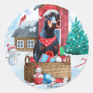 Pegatina Redonda Perro Doberman en casa de Navidad con nieve