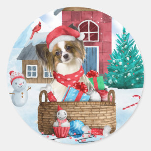 Pegatina Redonda Perro Papillon en casa de Navidad con nieve