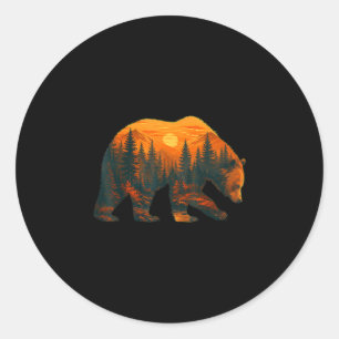 Pegatina Redonda Silueta de oso con paisaje forestal y puesta de so