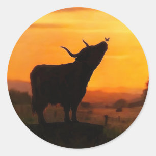 Pegatina Redonda Vaca o ternero de las Tierras Altas y puesta de so