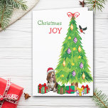 Perro, pájaro y árbol de Navidad astronados<br><div class="desc">En la parte delantera de esta tarjeta de Navidades, un feliz perro del Basset Hound usa un gorra rojo y blanco de Santa Claus mientras se sienta junto a un árbol de vacaciones. Los paquetes de regalo envueltos de forma brillante están dispersos por todo el mundo, y un bullfinch está...</div>