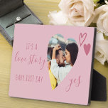 Placa Expositora Historia de amor dice sí propuesta rosa foto de co<br><div class="desc">Placa de la Propuesta de matrimonio con foto en forma de corazón romántico. Está escrito con "es una historia de amor, el bebé sólo dice que sí" en un guión elegante y decorado con corazones de amor rosados. Perfecto apoyo y mantenimiento para su propuesta matrimonial y invitación de compromiso. El...</div>