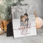 Placa Expositora Primer guión rojo de Borgoña de Navidad<br><div class="desc">Conmemorar su compromiso con esta hermosa placa moderna de keepsake. El texto rojo burdeos dice "Nuestra primera Navidad se comprometió", con la palabra "comprometida" en un elegante guión de escritura a mano con flores antes y después. Reemplace la imagen de ejemplo con su foto favorita y agregue sus nombres y...</div>