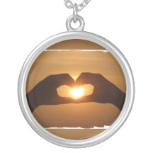 Collar de la puesta de sol en las manos del corazó