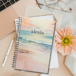 Playa Sunrise | Planificador anual personalizado d<br><div class="desc">Manténgase organizado e inspirado con nuestro planificador de personalizables que presenta un diseño de playa tropical con una suave escena de playa de amanecer en la parte delantera y trasera. Personalízalo con tu nombre y el año para un planificador que sea único suyo. Con un amplio espacio para programar, tomar...</div>