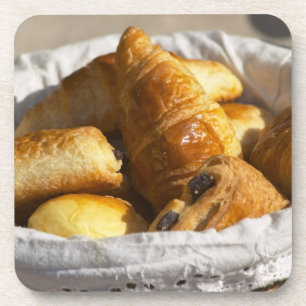 Posavasos Una cesta de desayuno de mimbre con cruasanes, y