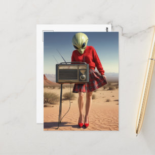 Postal Alienígena en la falda roja con radio en el desier