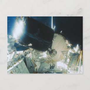 Postal Astronautas reparan un satélite en el espacio