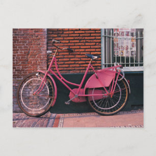 Postal Bicicleta rosa contra la pared de ladrillos