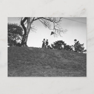 Postal Dos chicos volando cometas en la colina de B&W