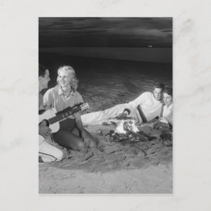 Postal Dos parejas en la playa sentadas alrededor de una 