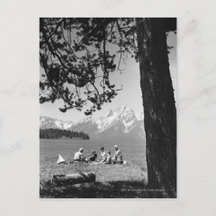 Postal Familia haciendo picnic por las montañas del lago