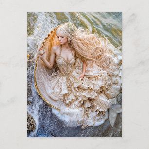 Postal Festiva Sirenita sentada en una concha gigante en la costa