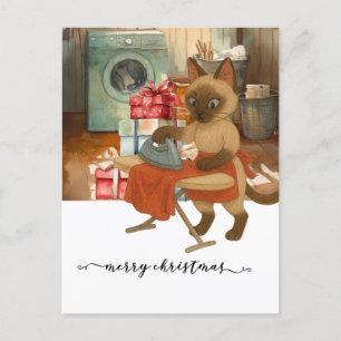 Postal Festiva Un gato siamés plancha un vestido para Navidades