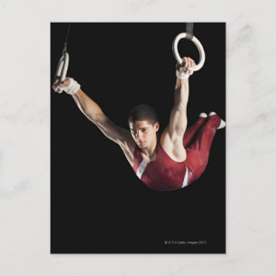 Postal Gimnasta columpiándose de anillas