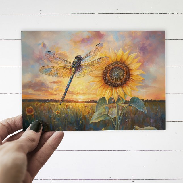 Postal Libélula Irisada Girasol Rústico (Postcard with a dragonfly and a sunflower being held up by a hand, over a white wood background.)