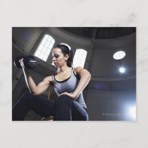 Postal Mujer joven haciendo ejercicio con dumbbell