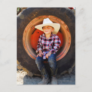 Postal Niño (4-7 años) sentado en un neumático tractor.