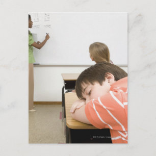 Postal Niño durmiendo en un escritorio en un aula