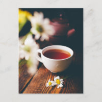 Taza de té negro y dos flores de camomila