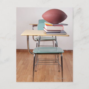 Postal Un escritorio estudiantil con un futbolín sentado 