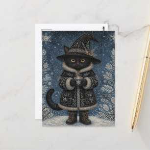 Postal Un gato bruja negro en la nieve con cacao caliente