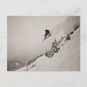 Postal Un snowboard salta de un acantilado a polvo en