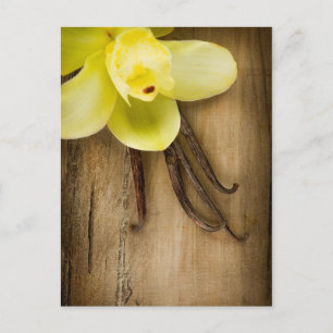 Postal Vanilla Pods and Flower over Wooden Background