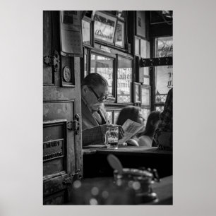 PÓSTER FOTO DE GREYSCALE DE HOMBRE SENTADO MIENTRAS LEÍA 