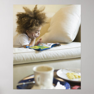 Póster Mixed race boy reading book on sofa