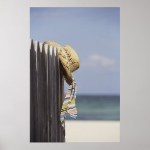 Póster Straw Hat Hanging On Fence At Beach