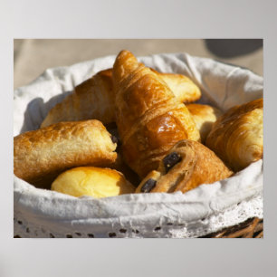 Póster Una cesta de mimbre para desayuno con croissants, 