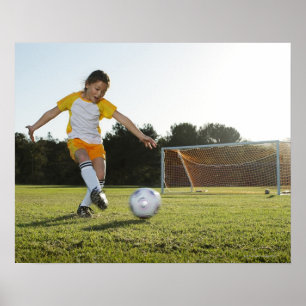 Póster Una chica joven que juega a fútbol en un campo de