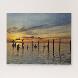 Puzzle Puesta de sol con postes de madera en el agua