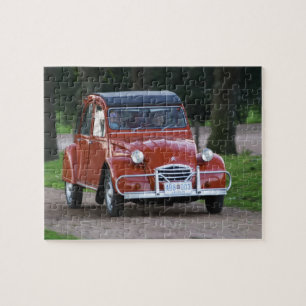 Puzzle Un viejo coche rojo Citroen 2CV con una mujer sonr