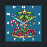 Reloj Cuadrado Árbol de palmas de Navidades tropicales<br><div class="desc">Un reloj con una imagen de temporada. Una palmera tropical adornada con luces festivas y una estrella en la parte superior. Un enorme bastón de caramelo rojo y blanco saliendo de la arena. Regalos de Navidad debajo del árbol. Genial y divertido.</div>