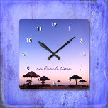 Reloj Cuadrado En tiempo de playa Fotografía morada rosada de Cal<br><div class="desc">"A la hora de la playa". Una puesta de sol azul violeta y rosa en una playa del sur de California con palapas de paja rebosa de relajación y reflexión. Relájese, huela el aire del océano y recuerde los recuerdos de verano cada vez que mire la hora de esta moda,...</div>