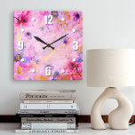 Reloj Cuadrado Moda romántica de color dorado rosa rosa de color<br><div class="desc">Numerales audaces, blancos fáciles de leer, junto con flores color de agua rosadas, púrpura y azul, superponen el guión dorado en un fondo suntuoso, rosa, morado y dorado. Relájese en su habitación favorita con este moda, impresionante y elegante reloj de pared. Tu elección de una cara de reloj redonda o...</div>