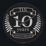 Reloj Redondo Grande Marfil Aniversario del boda tradicional de 10 años<br><div class="desc">Un diseño para celebrar 10 años de matrimonio. Este diseño tiene un diseño de laurel de color gris / plata (el color tradicional para este aniversario) sobre un fondo negro. Tin es el regalo tradicional para esta ocasión. El texto dice el décimo aniversario de Tin. Un diseño romántico para celebrar...</div>