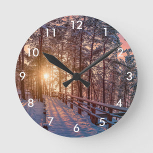 Reloj Redondo Mediano Atardecer en un bosque de pinos nevado con rayos s