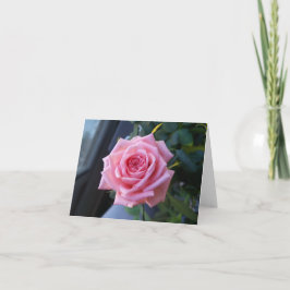 Rosa rosado en una tarjeta de nota en blanco