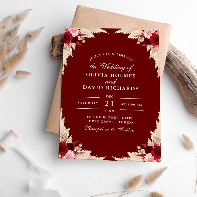 Rosas de Borgoña y la invitación a la boda de Gras (Burgundy Roses and Pampas Grass Wedding Invitation on a table with pampas grass.)