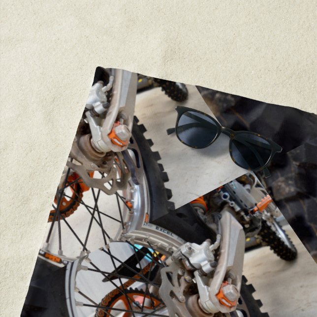 Rueda de bicicleta sucia, toalla de playa (In situ)