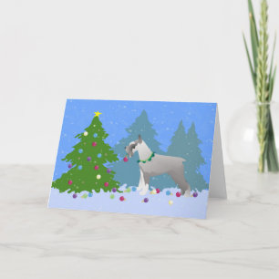Schnauzer decora el árbol de Navidad en el bosque