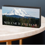 Señal Decorativa De Madera Bienvenida del paisaje del Monte Rainer<br><div class="desc">Una casa acogedora, símbolo de la caja de madera diseñado para colgar o pararse que presenta una imagen panorámica de paisaje fotográfico de la nieve cubierta del Monte Rainier y un valle verde en el estado de Washington, al noroeste del Pacífico. Las letras en negrita y en blanco dicen: "BIENVENIDOS...</div>