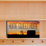 Señal Decorativa De Madera Hogar Sweet Home Sunset Silhouette<br><div class="desc">Cartel de una caja de madera pintada de negro, diseñado para colgar o estar de pie, que muestra la imagen de una puesta de sol colorida y la silueta negra de una casa junto con las palabras "HOGAR HOGAR DULCE" impresas en letras grandes y negras. ¡Un dulce agregado a cualquier...</div>