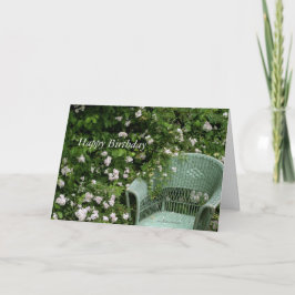 Silla de mimbre entre flores Tarjeta de felicitaci